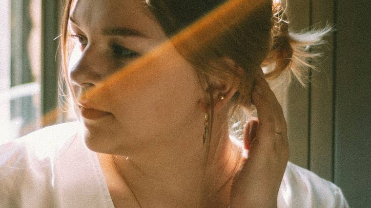 A woman turning her ear towards the light, listening intently